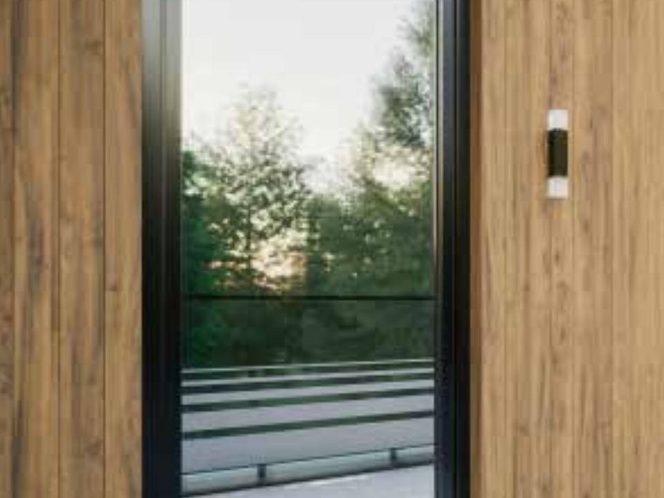 Porte-fenêtre PVC avec capotage aluminium noir dans un mur bardé de bois
