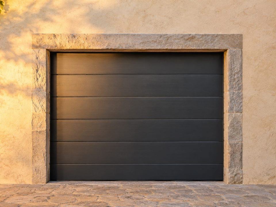 Porte de garage sectionnelle anthracite à panneaux horizontaux dans une façade en pierre